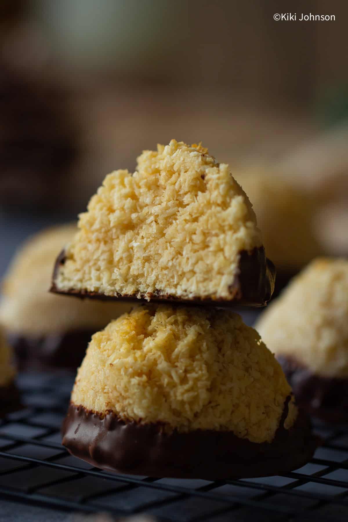 two stacked coconut macaroons dipped in dark chocolate on a cooling rack. 