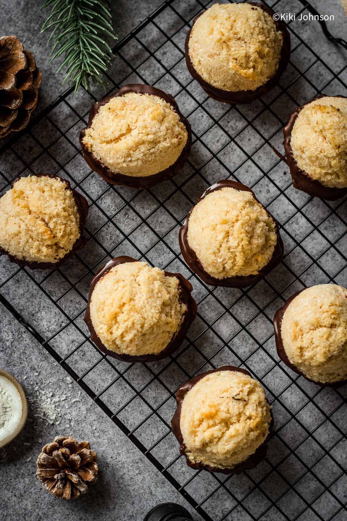 coconut macaroons with salted caramel dipped in melted chocolate on a cooling rack.