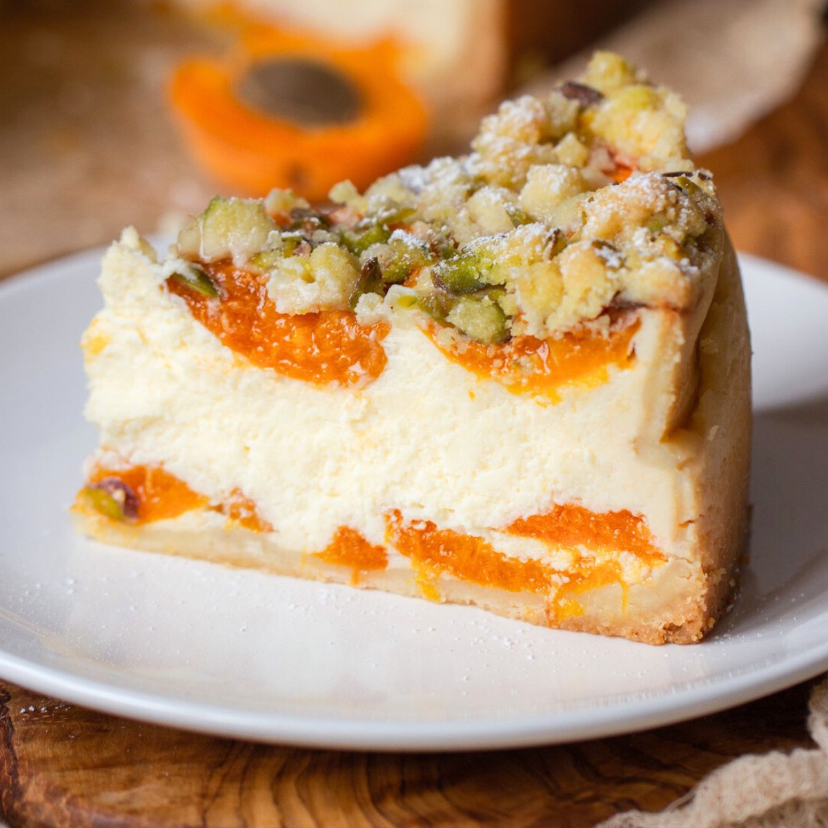 ein Stück marillenkuchen mit topfen und streusel auf einem braunen Kuchenteller