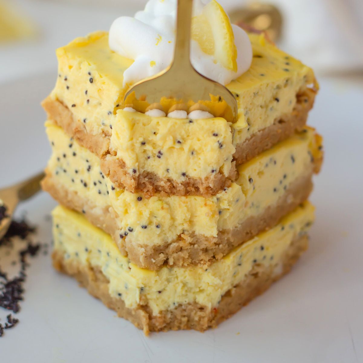 drei stuecke zitronen mohn kaesekuchen vom blech mit einem Tupfen Sahne dekoriert