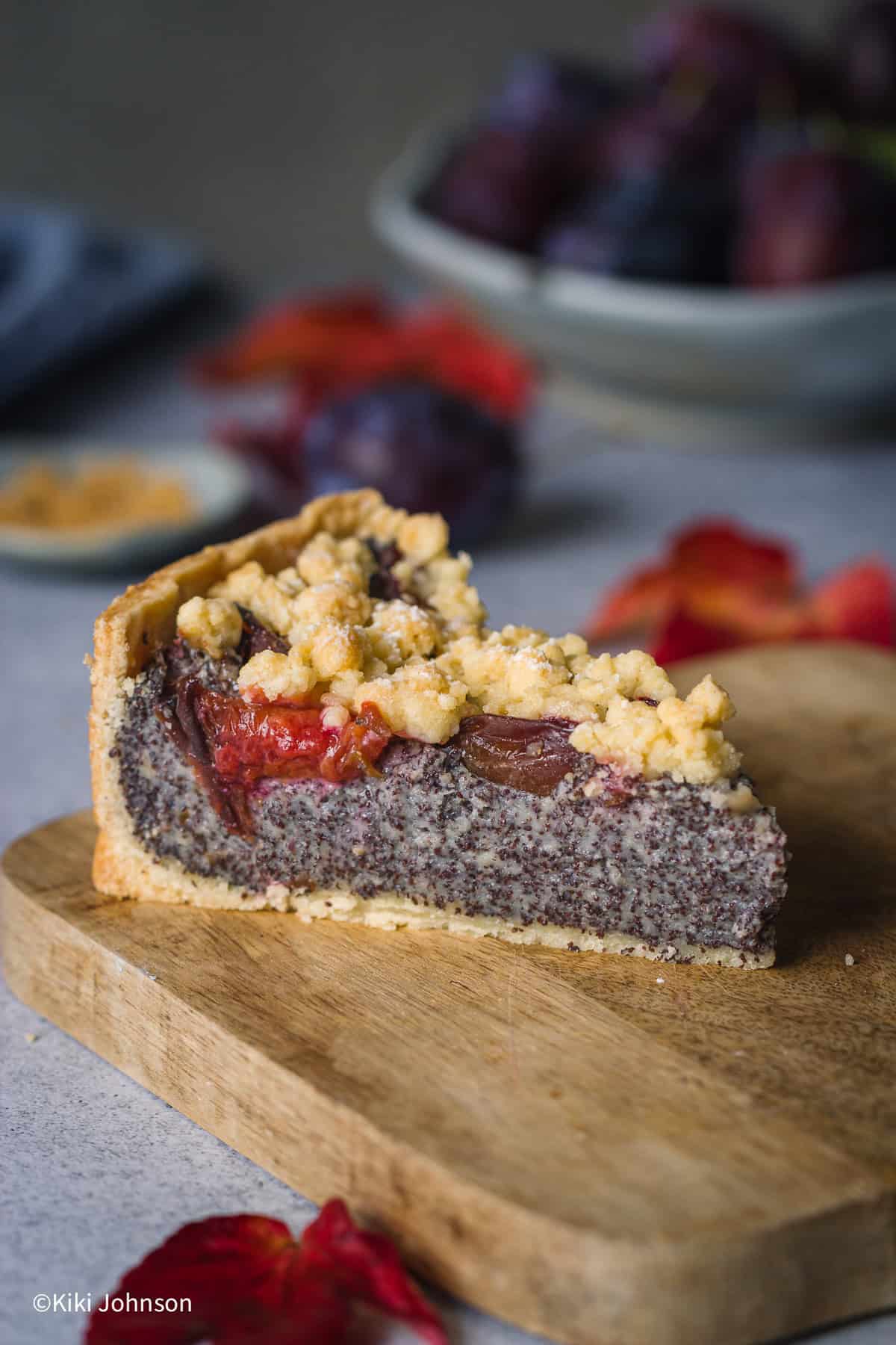 a slice of German poppy seed cake with homemade poppyseed filling and prune plums topped with streusel topping