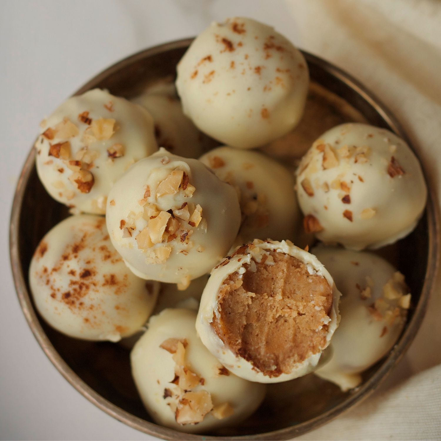 eine schale mit gebrannten mandel pralinen mit weisser kuvertüre überzogen