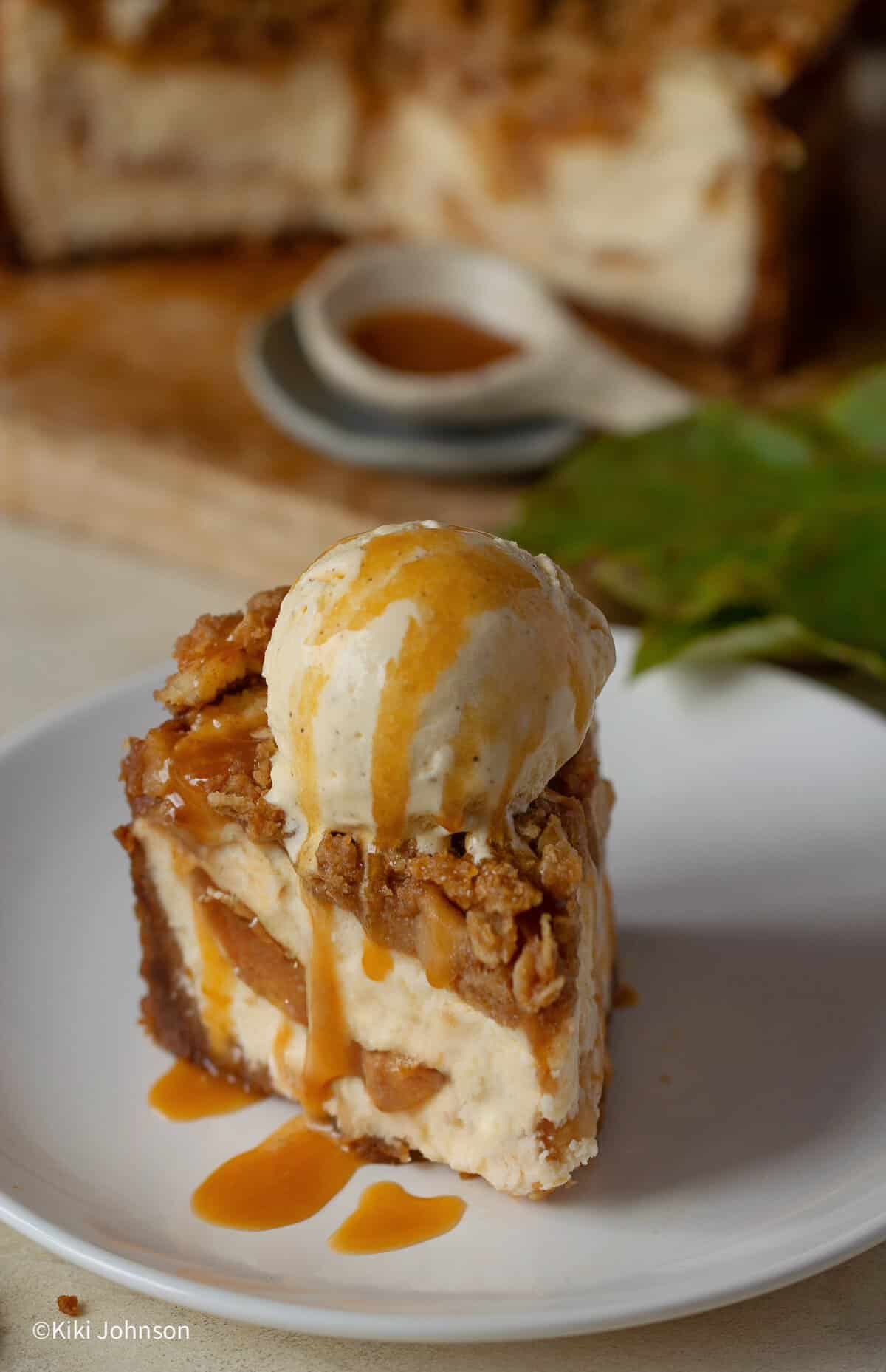 ein Stück  Apfel Käsekuchen mit Keksboden & Streuseln mit einer Kugel Eis serviert.