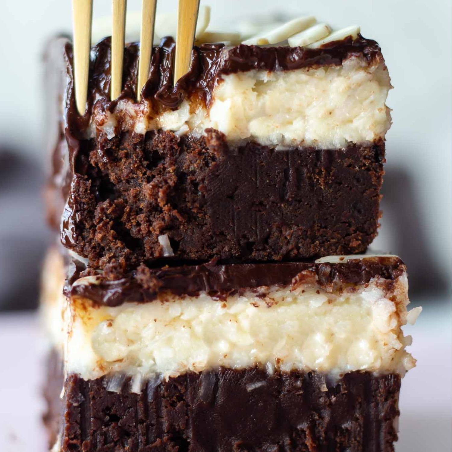 a stack of two bounty brownies with chocolate ganache on top