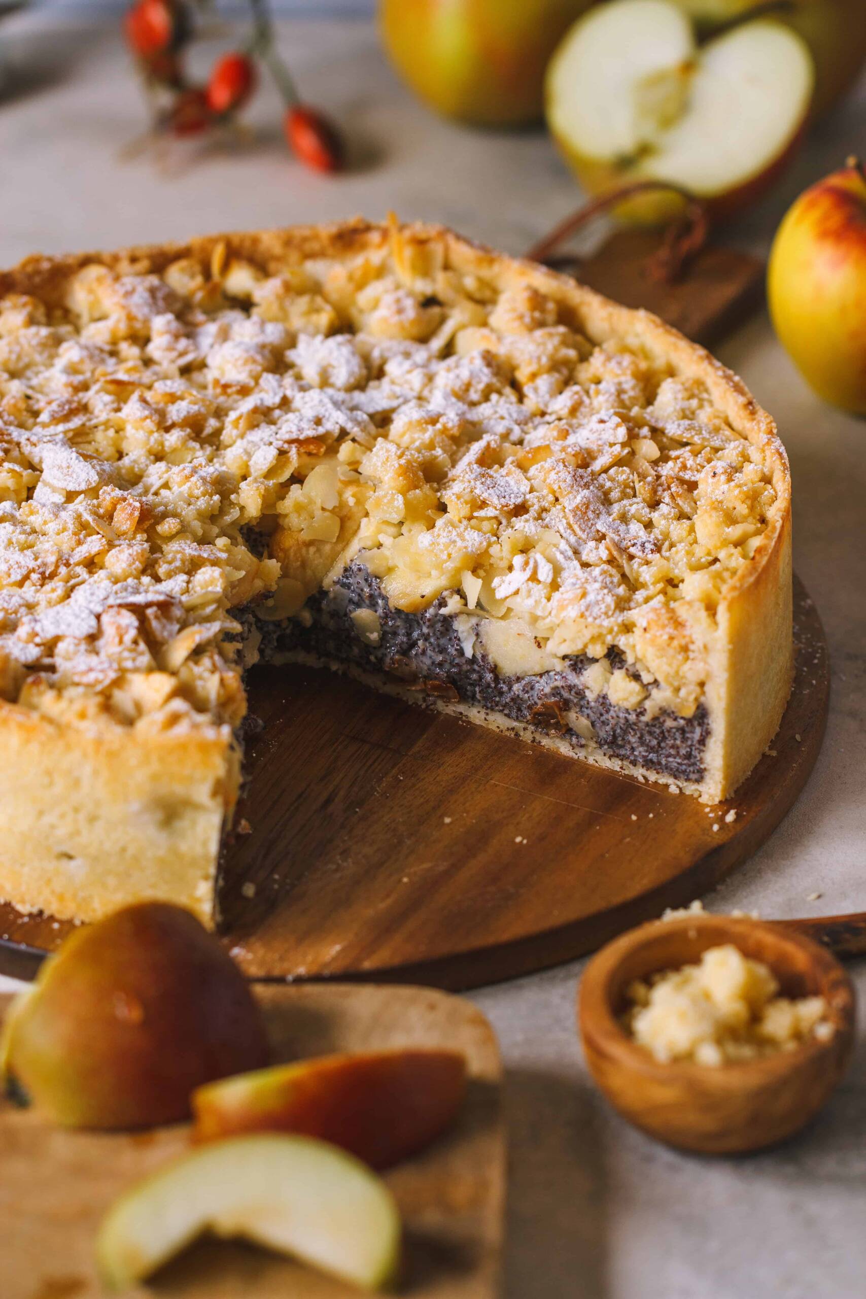 ein angeschnittener Mohnkuchen mit Rumrosinen, Äpfeln und Streuseln 