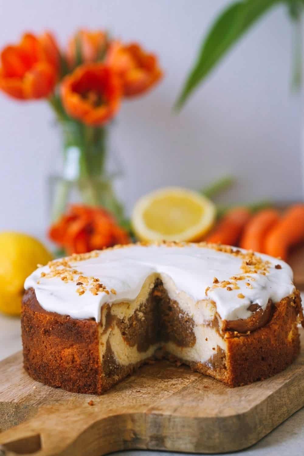 ein angeschnittener Carrot Cake Cheesecake auf einem Holzbrett