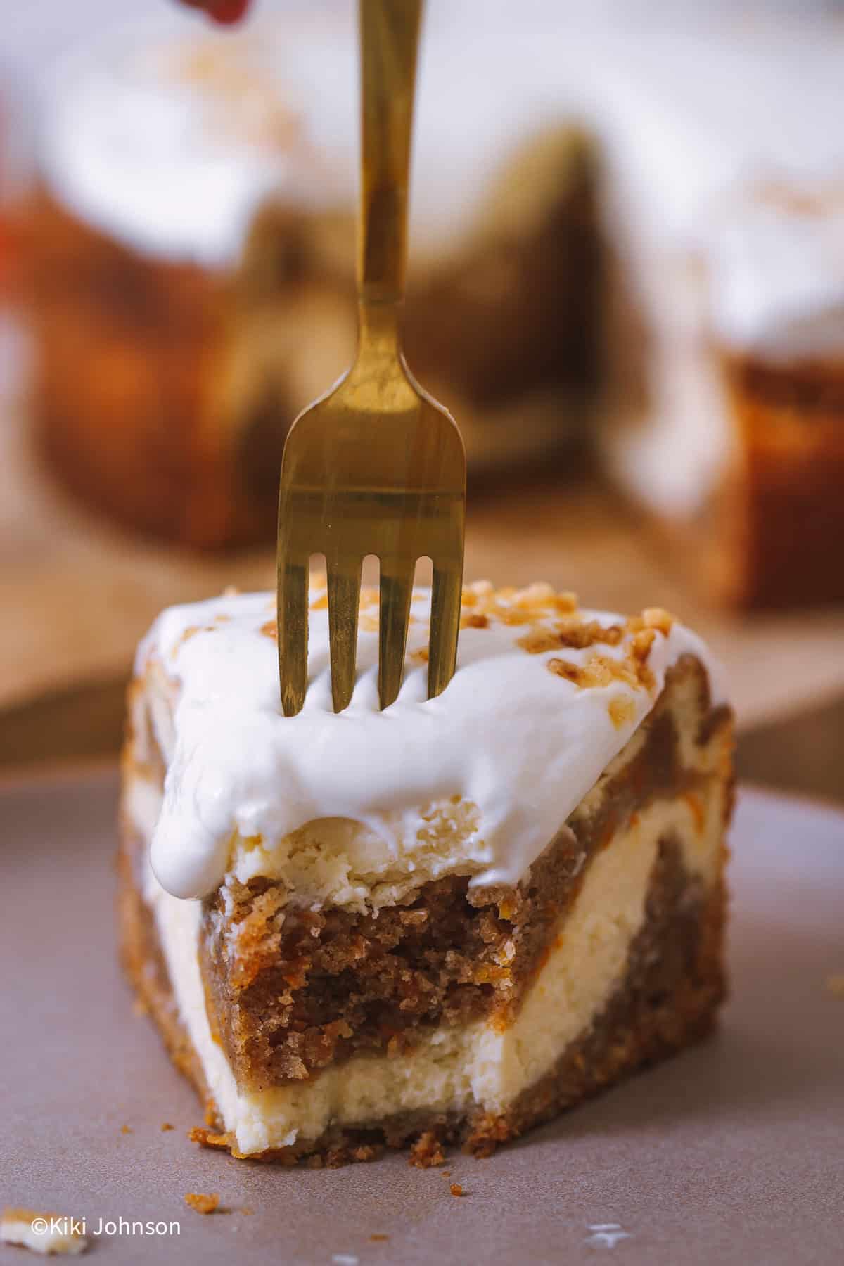eine Gabel sticht in ein Stück Carrot Cake Cheesecake mit Frischkäse Frosting