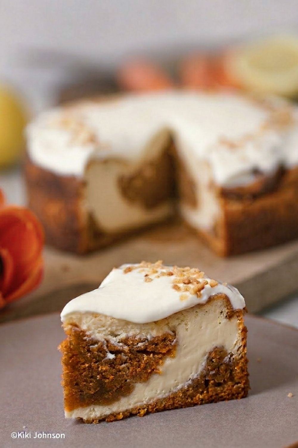 ein Stück Carrot Cake Cheesecake mit halb Käsekuchen halb Cheesecake Teig auf einem braunen Teller mit Frischkäse Frosting verziert 