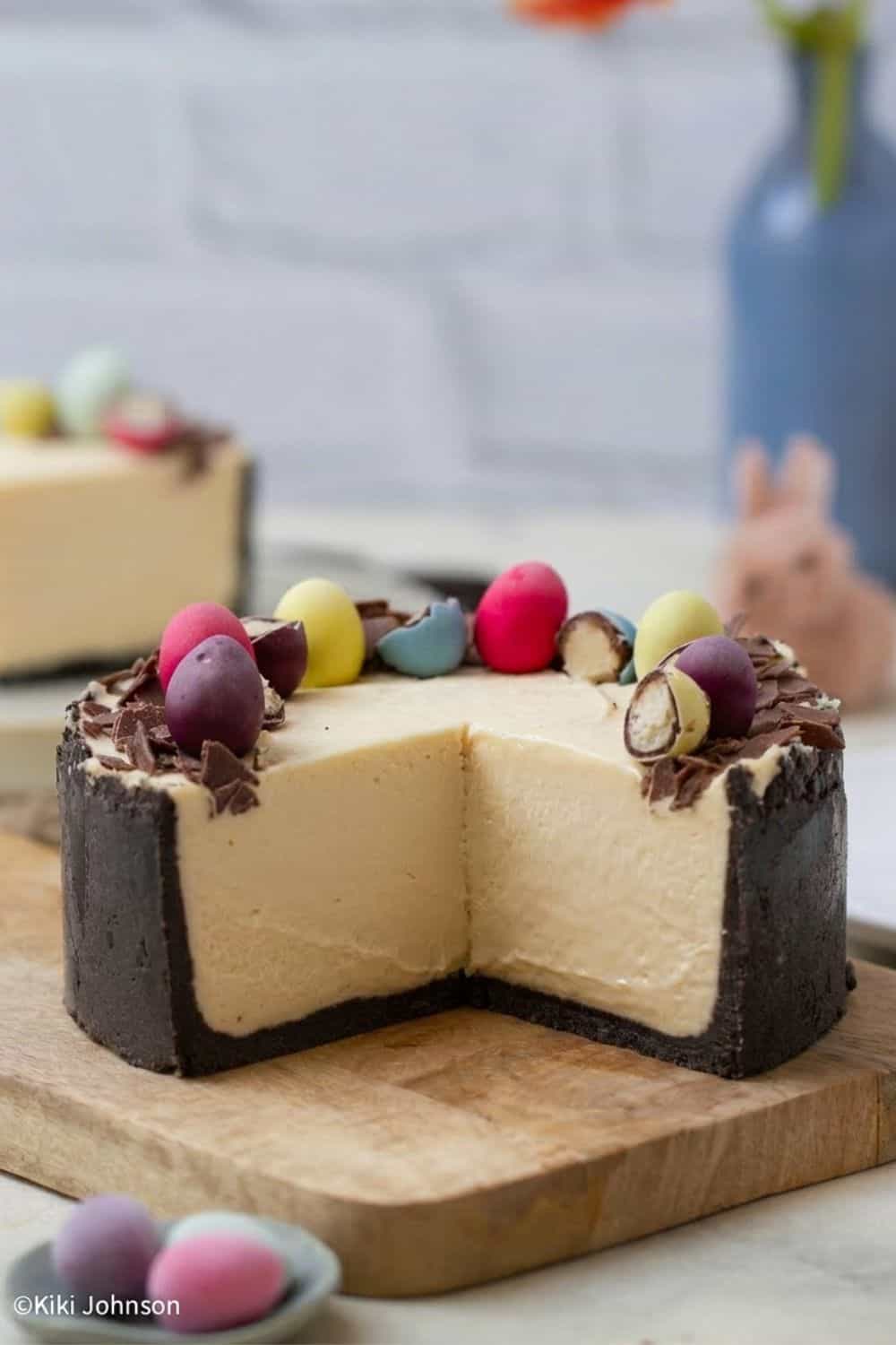 ein angeschnittener Haselnuss Cheesecake mit Oster Eiern dekoriert auf einem Holzbrett 