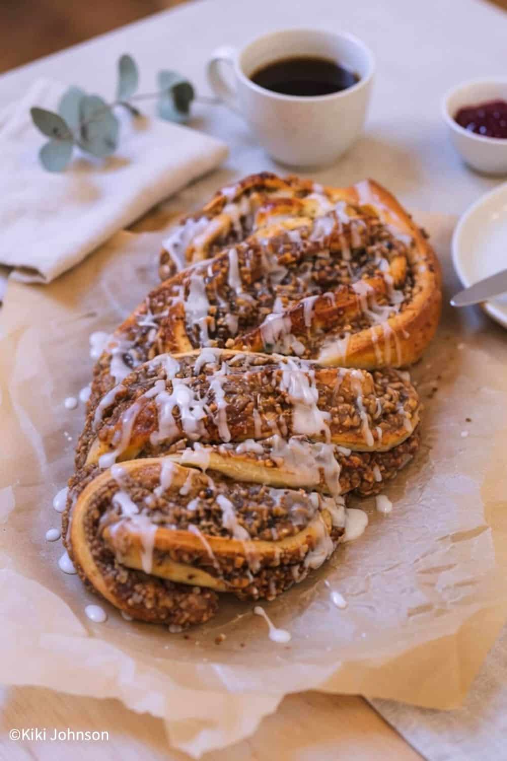 Omas saftiger Nusszopf mit Nussfüllung auf einem Stück Backpapier mit Zuckerguss