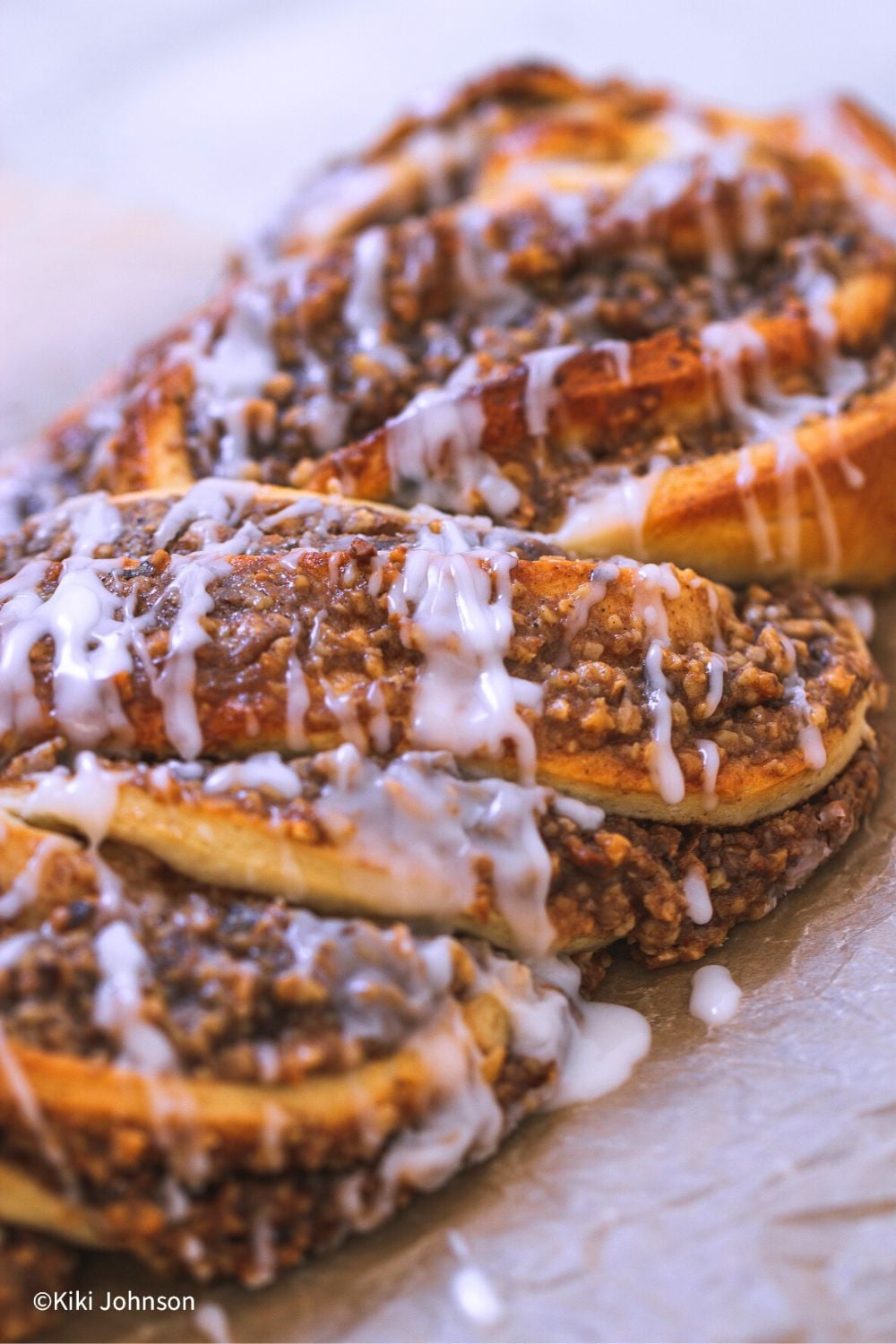 Seitenansicht von Nusszopf mit Zuckerguss auf einem Stück Backpapier