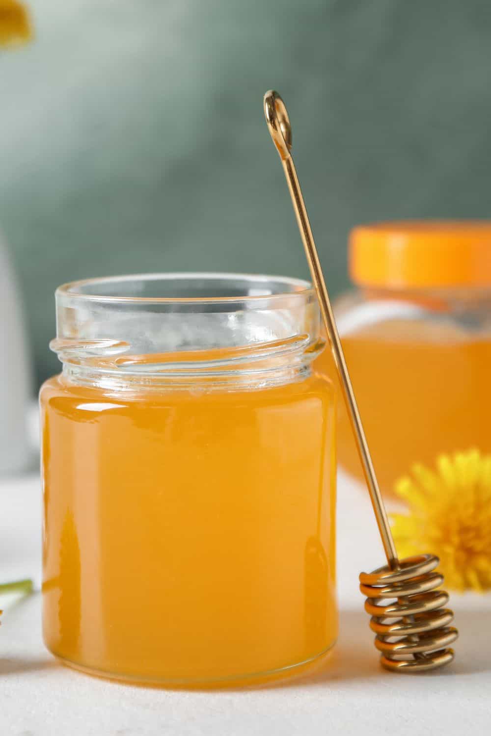 ein Glas selbstgemachter Löwenzahn Honig auf einer weissen Oberfläche