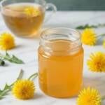 ein Glas Löwenzahn Honig auf einem Marmortisch mit einem Glas Tee im Hintergrund
