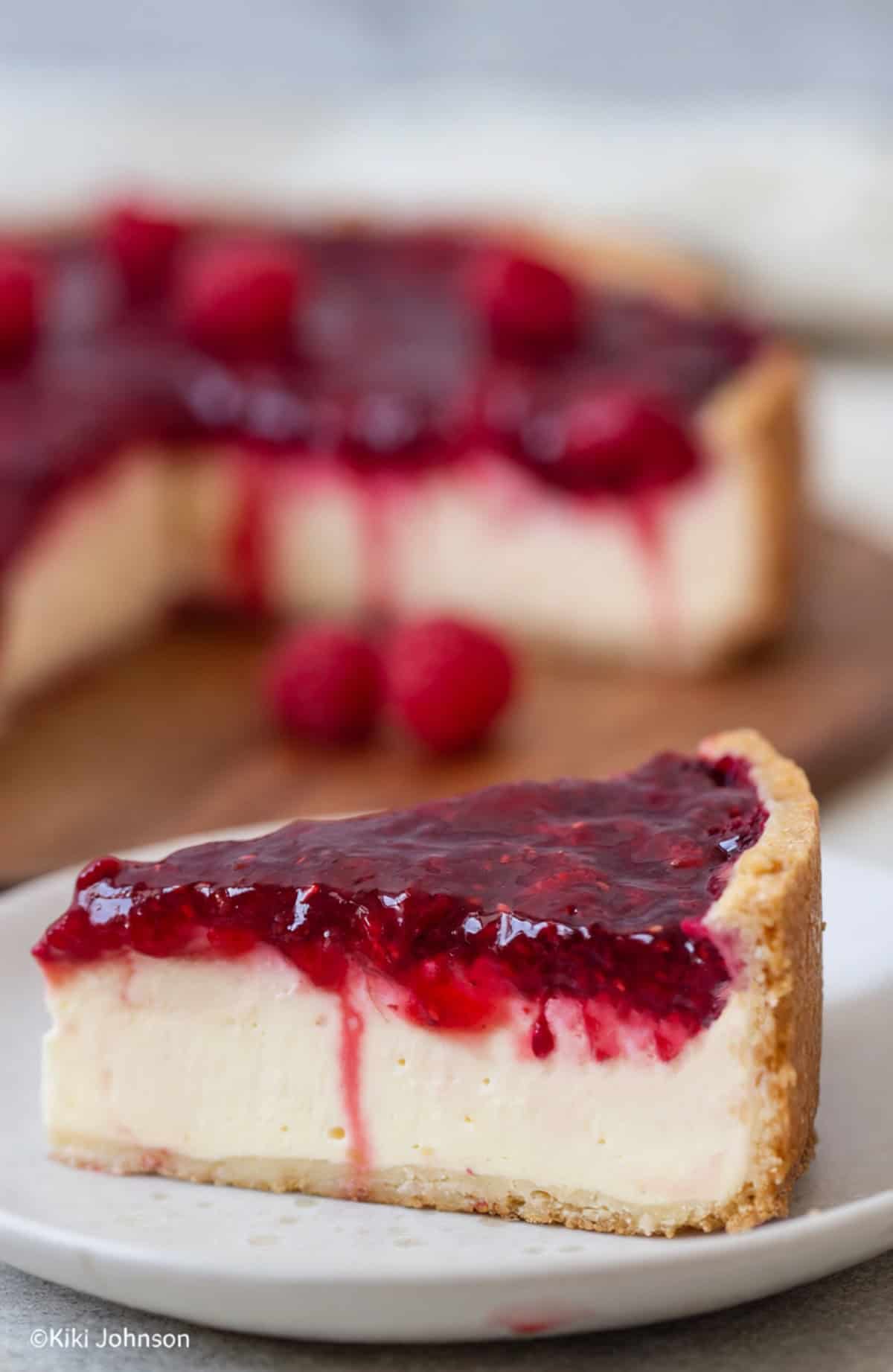 ein Stück cremiger Himbeer Schmand Kuchen auf einem weissen Teller