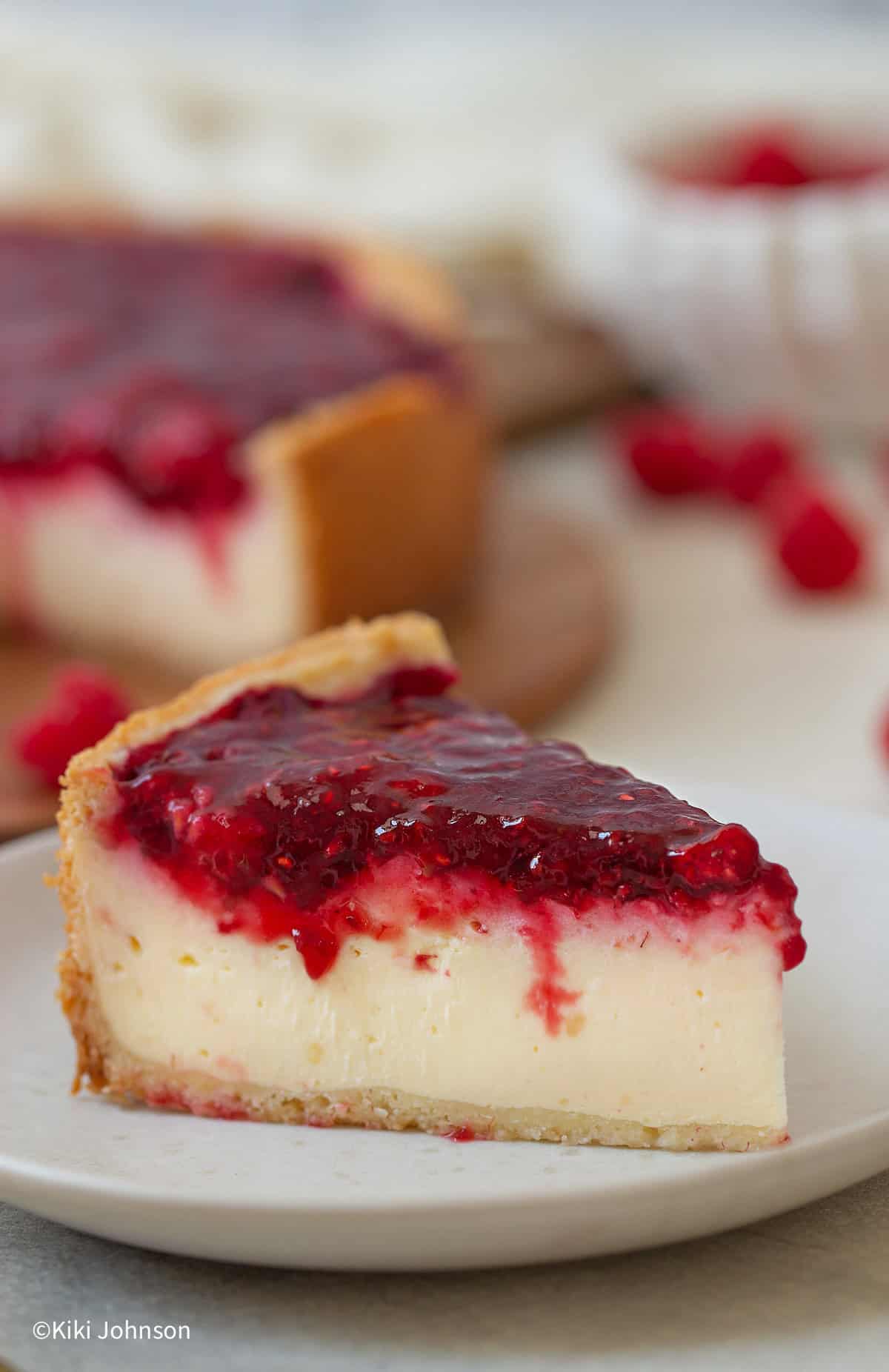 ein Stück cremiger Himbeer Schmand Kuchen auf einem weißen Kuchenteller