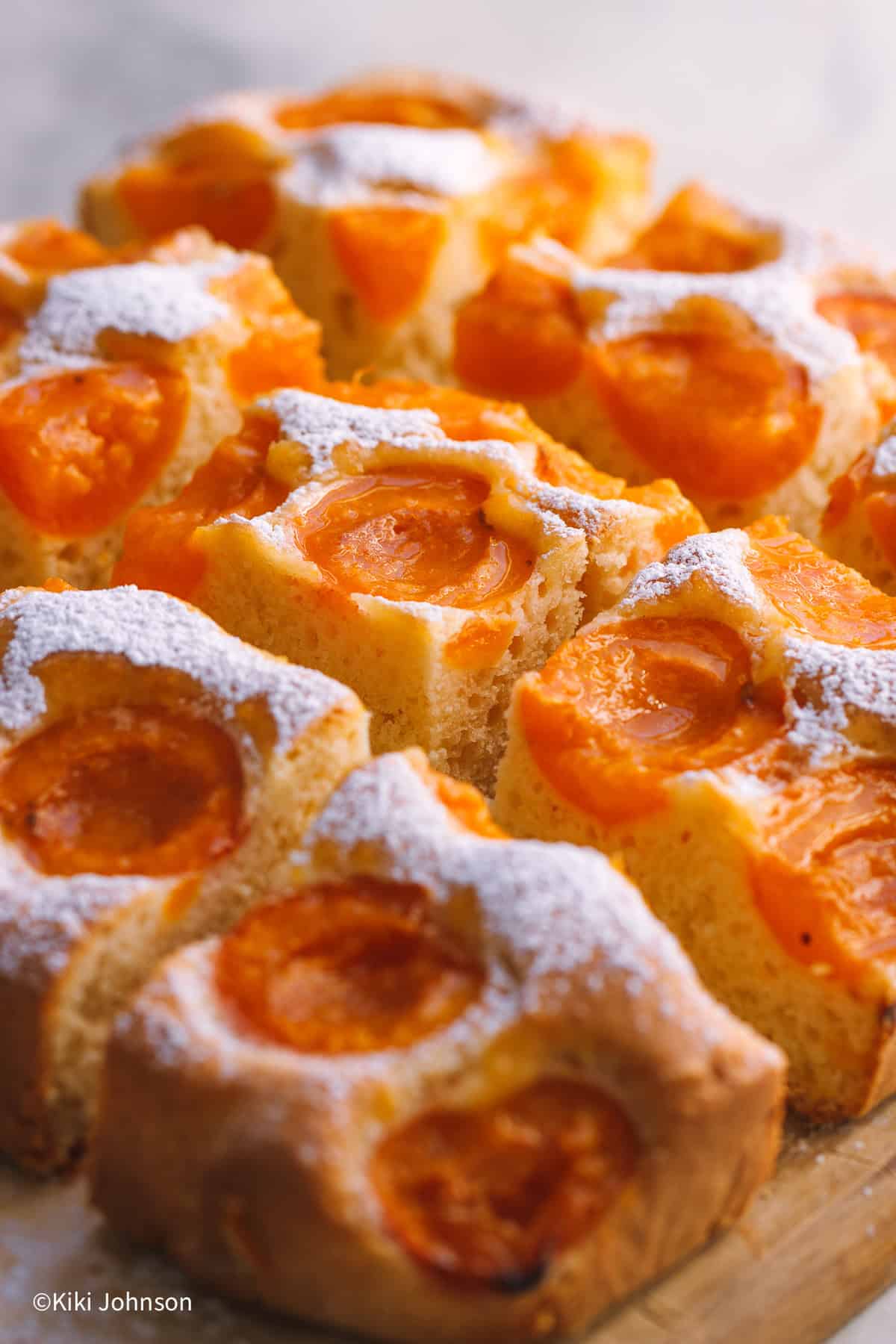 freshly baked Austrian Apricot Cake on a wooden board dusted with icing sugar.