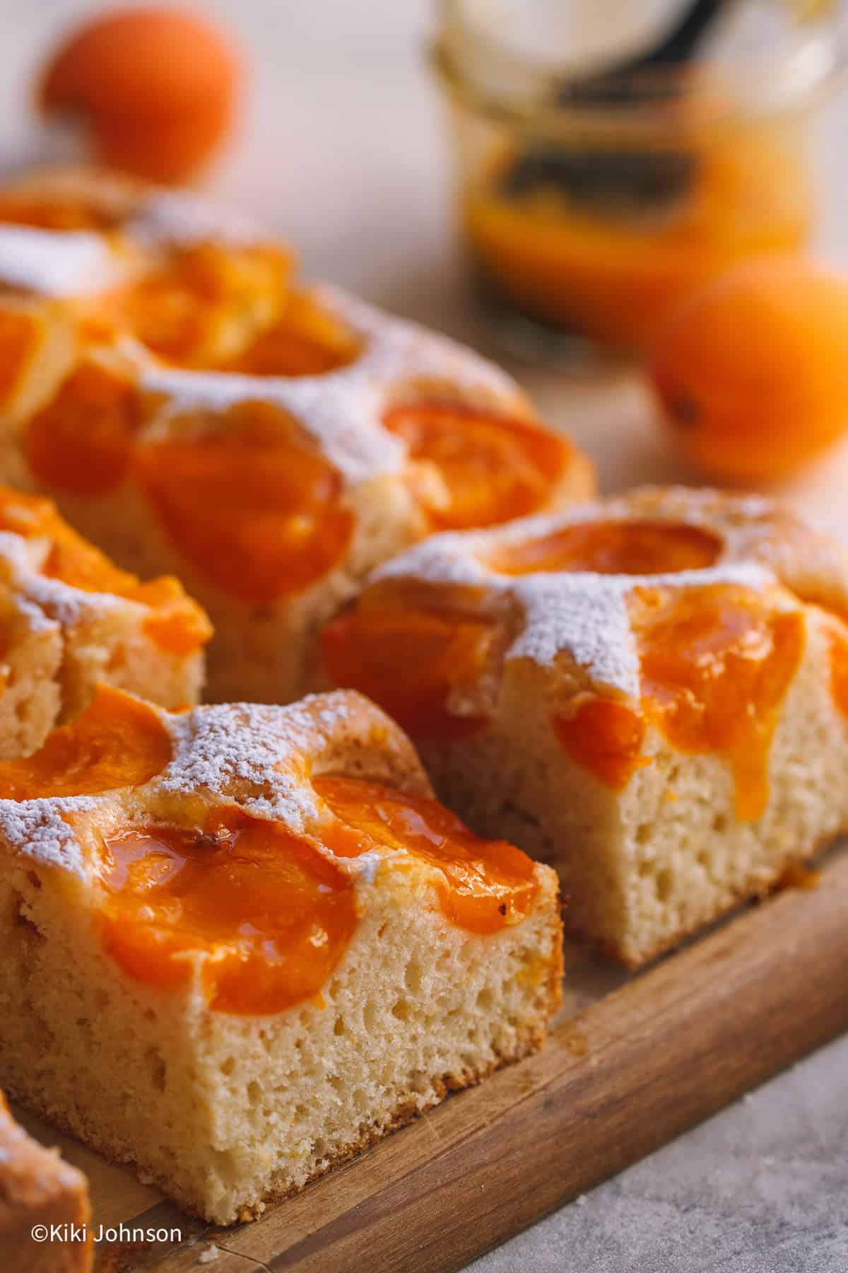 several sliced of Austrian Apricot Sheet Cake with a jar of apricot jam in the back 