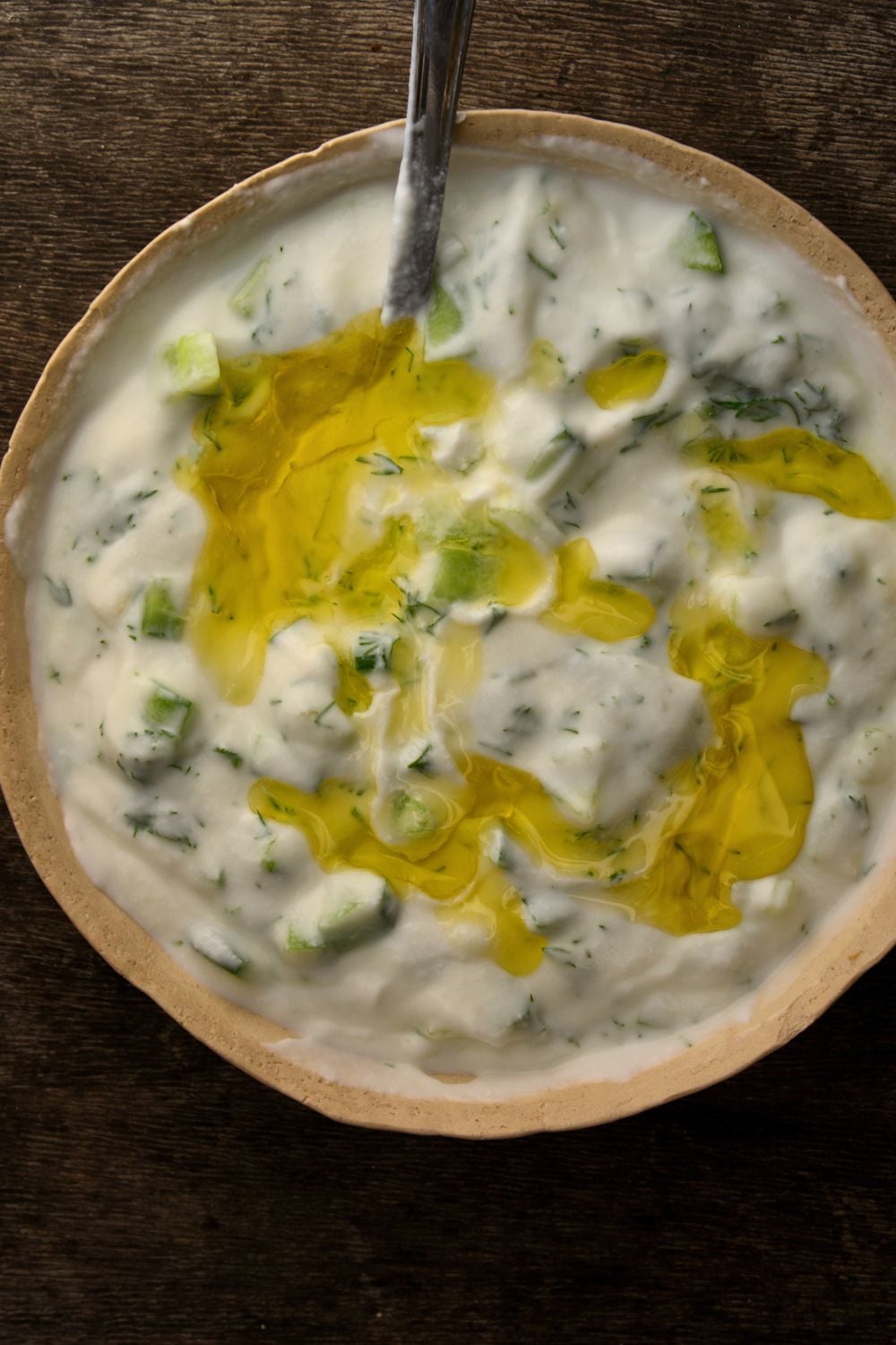 overhead shot of a bowl of tzatziki with a spoon in it 