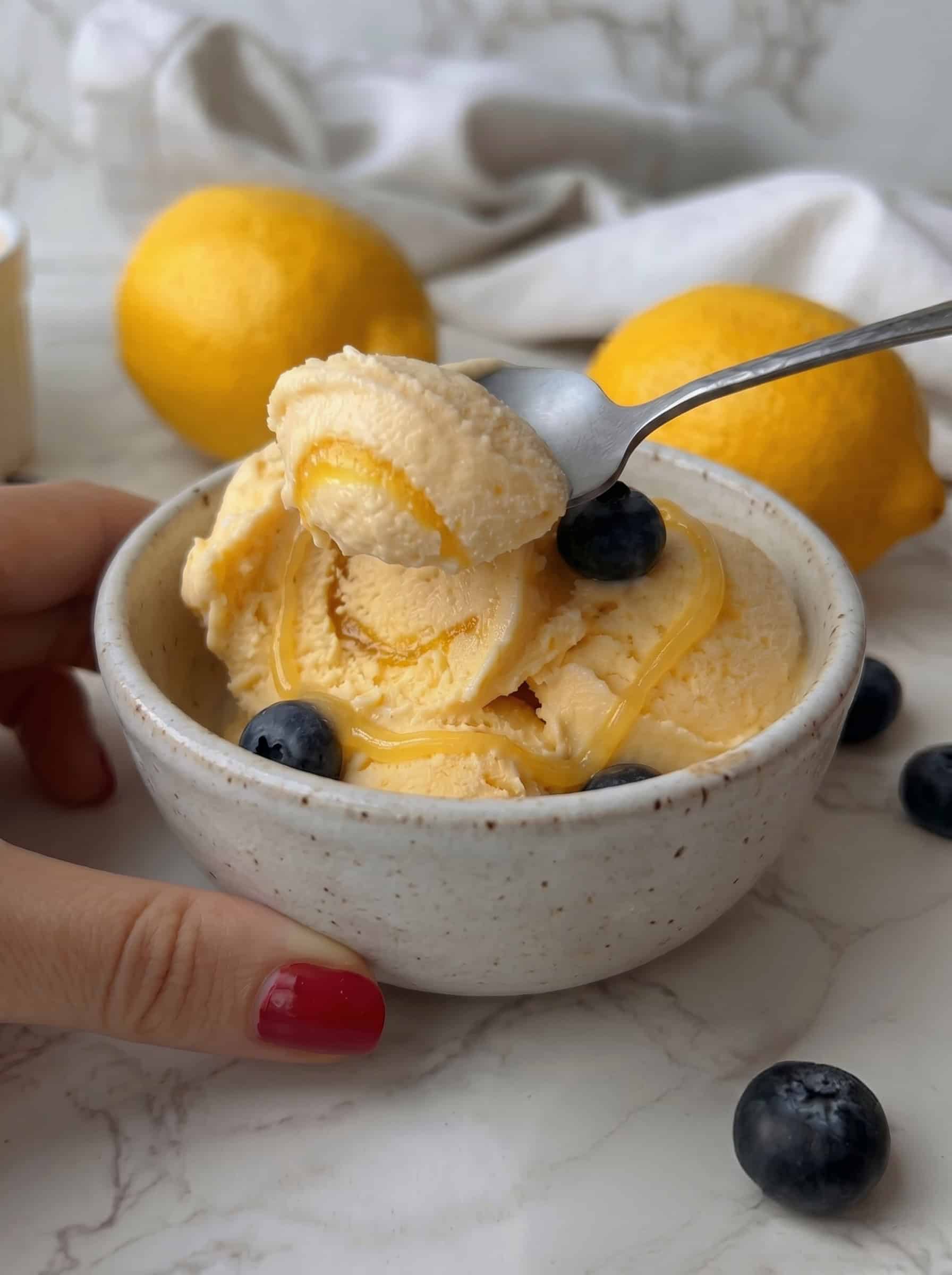 ein Löffel wird in eine Kugel selbstgemachtes Lemon Curd Zitroneneis gestochen