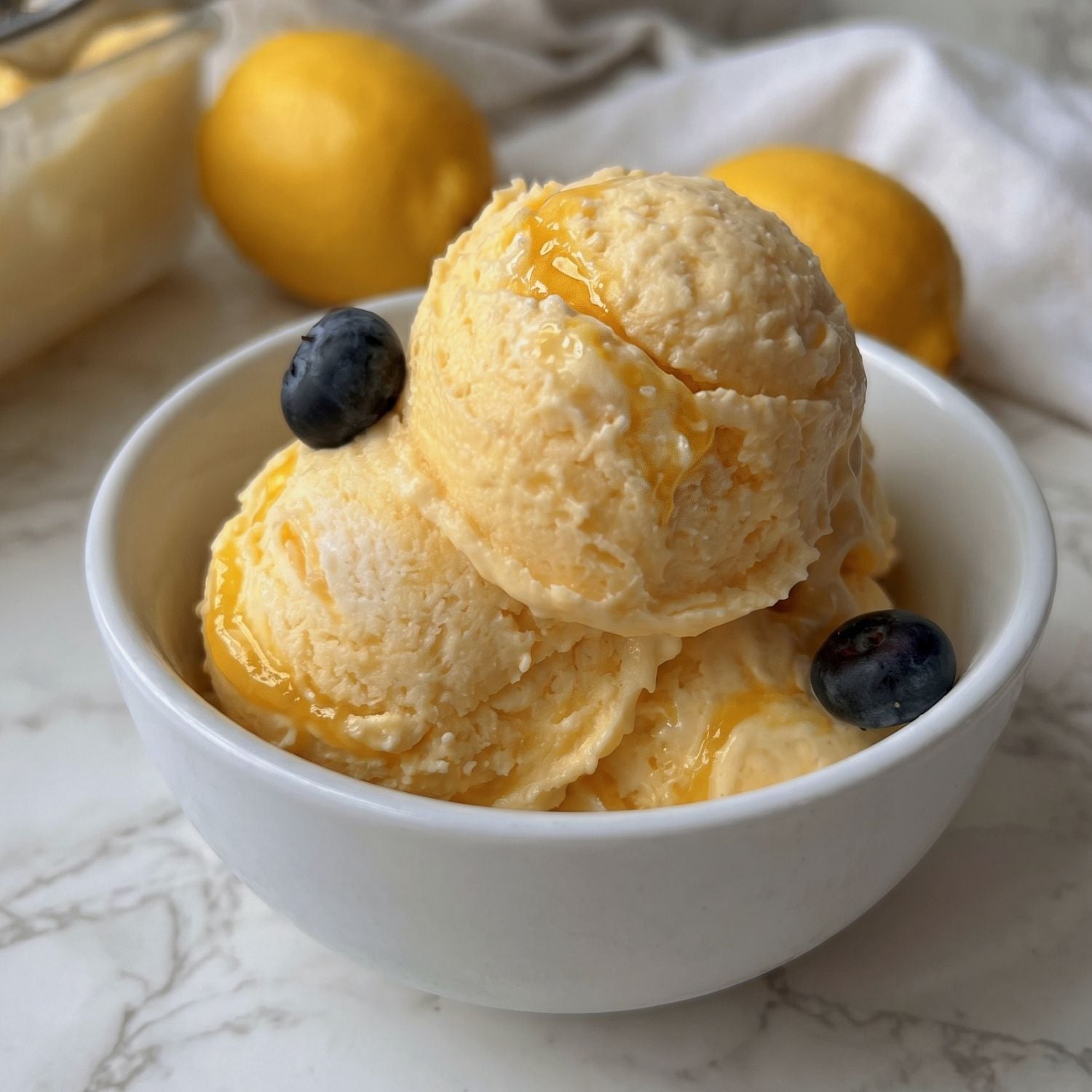 drei Kugeln Lemon Curd Eis in einer kleinen weissen SChale