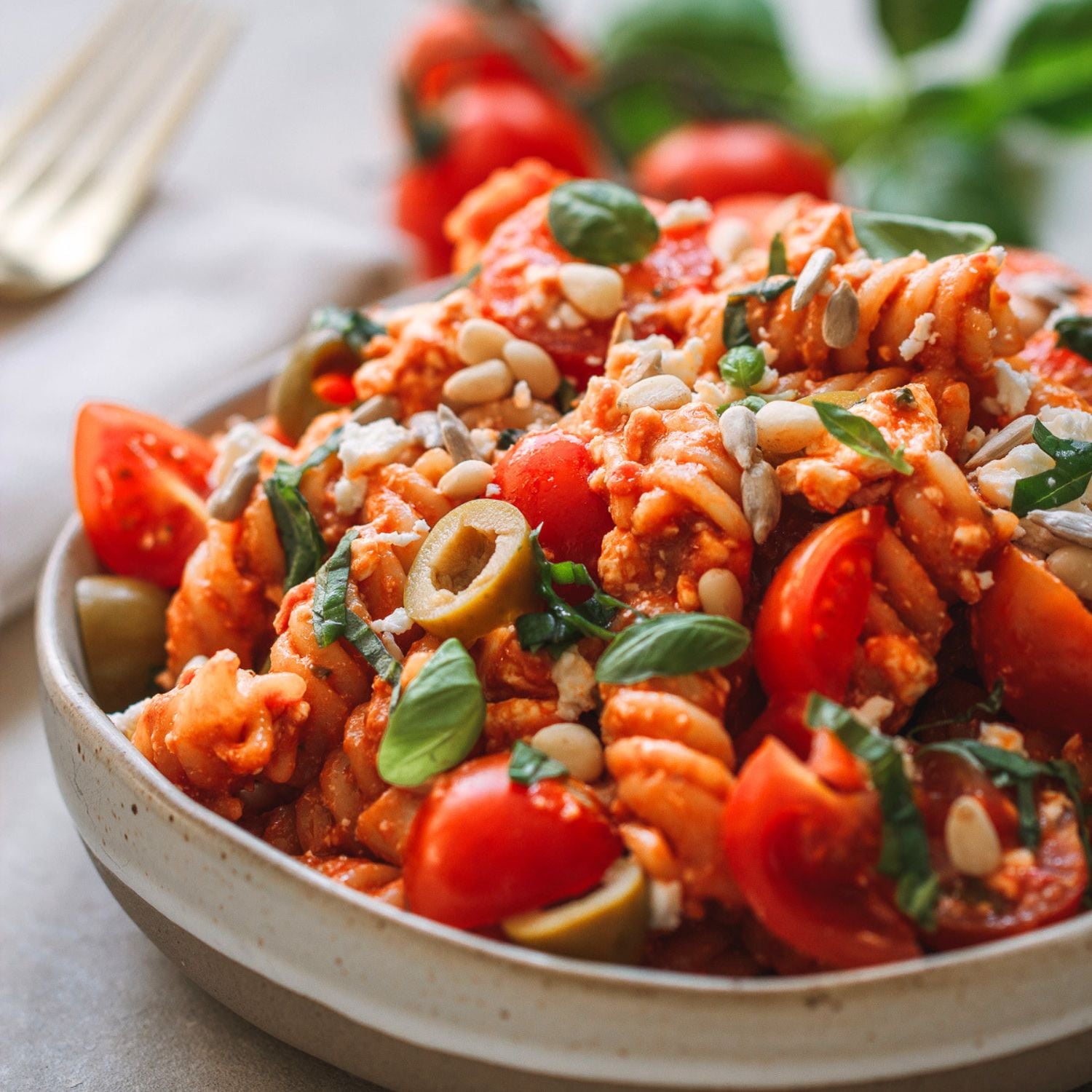 nudelsalat mit pesto, tomaten, oliven und feta in einer schale