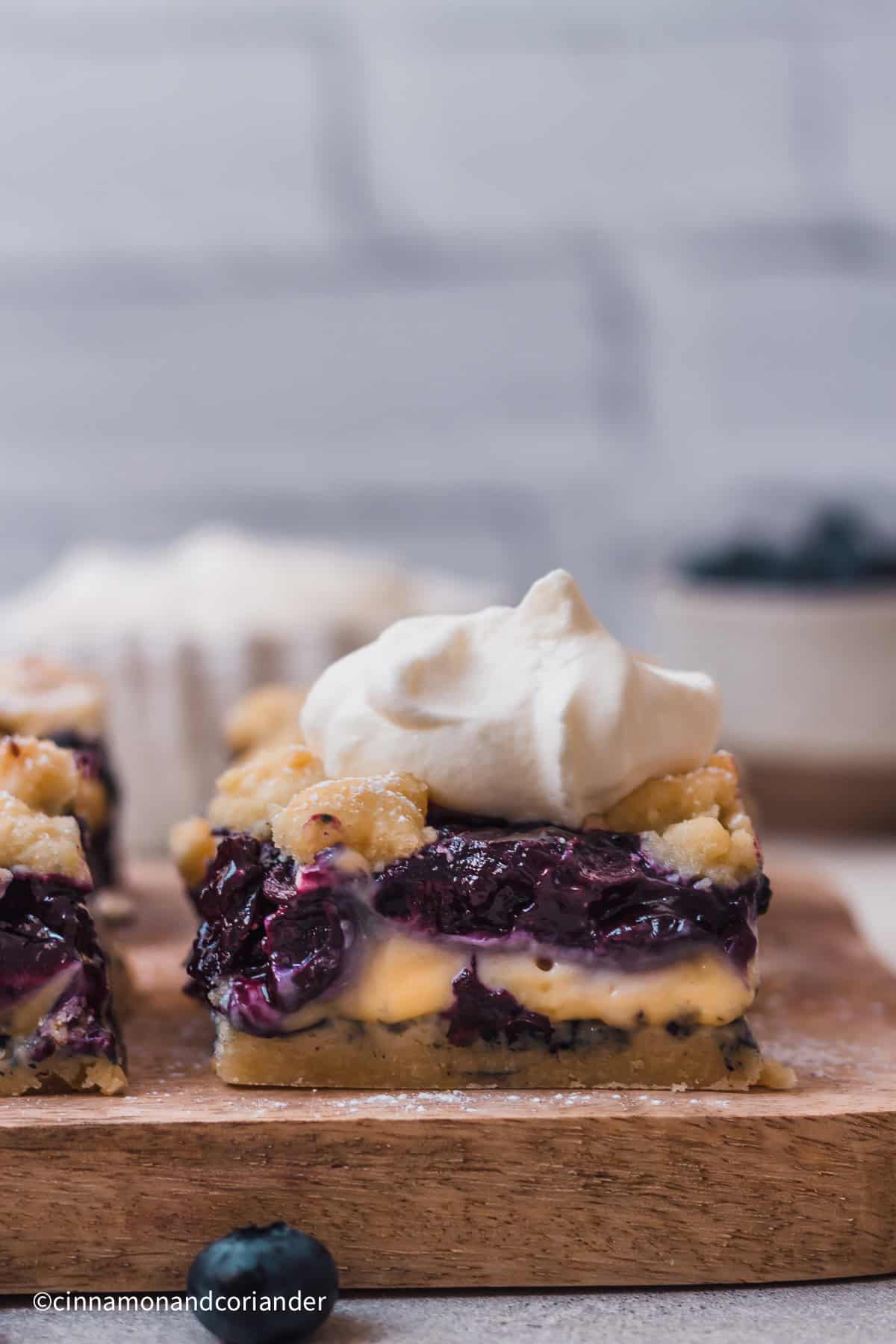 close up of a blueberry custard bar with homemade blueberry pie filling topped with whipped cream 