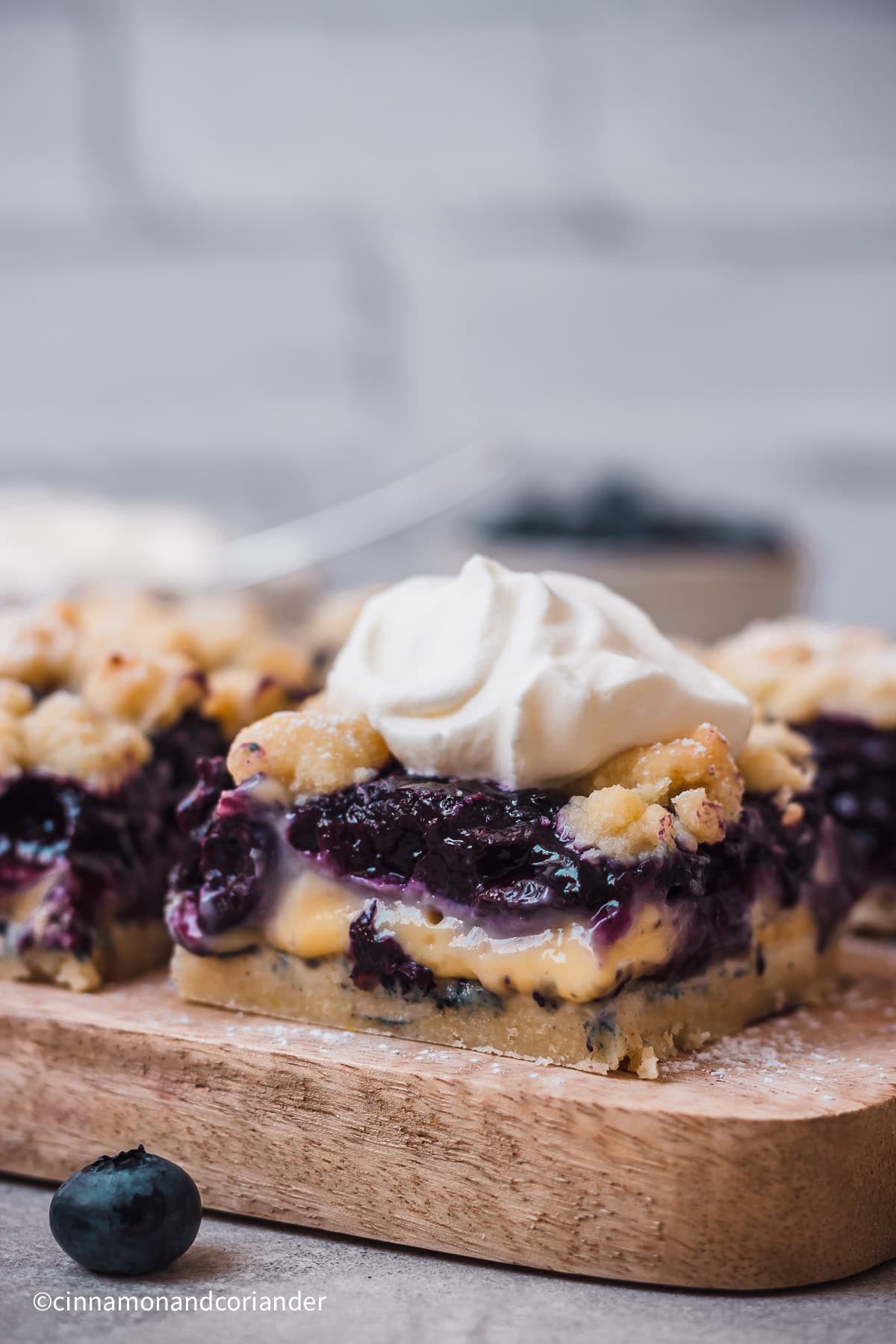 Blaubeerkuchen mit Pudding und Streuseln vom Blech mit einem Klecks Sahne serviert