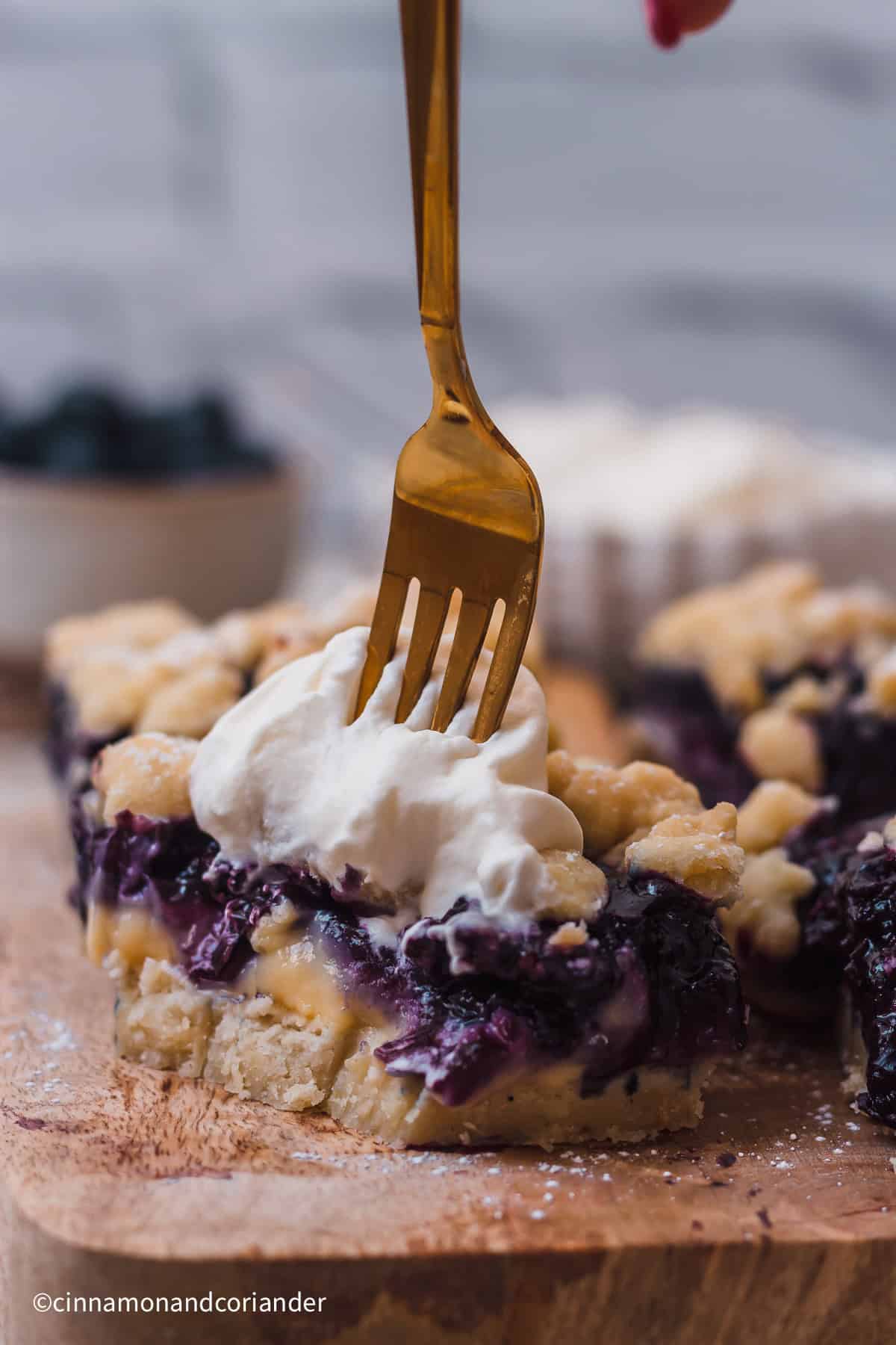 Eine Gabel sticht in ein Stück Blaubeer Pudding Kuchen mit Streuseln vom Blech