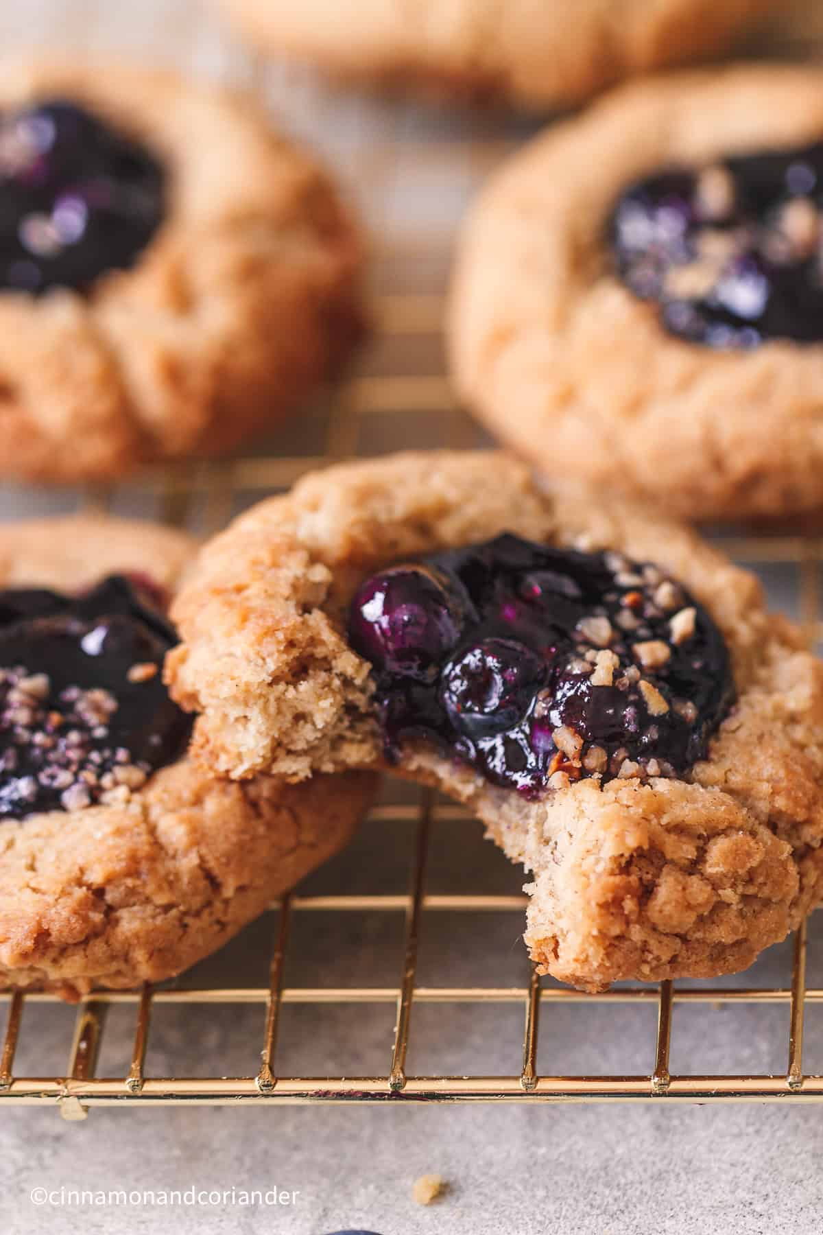 macro close up of stacked  blueberry pie cookie with homemade  blueberry jam filling on a golden cookie rack 