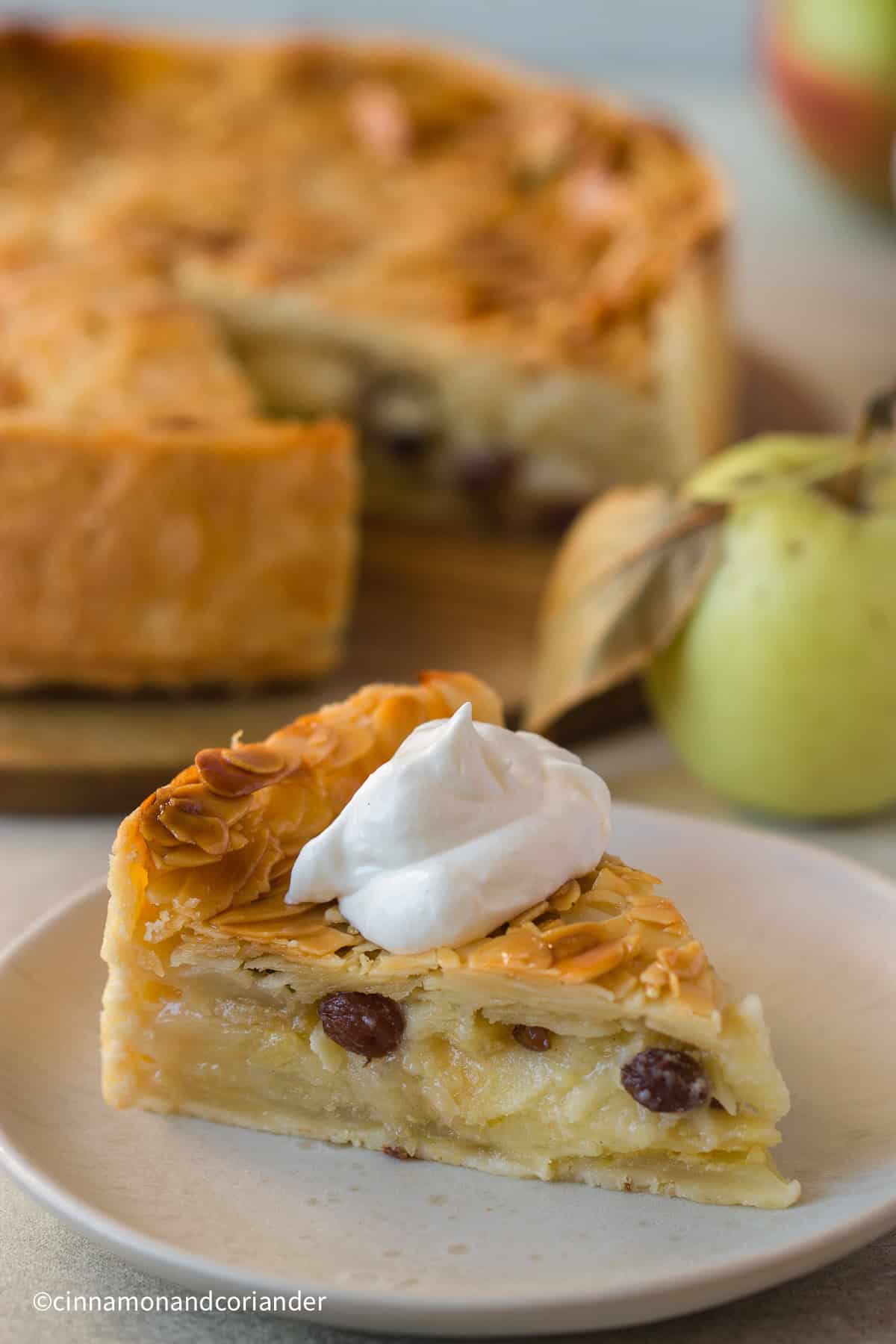 a slice of Florentine Apple Cake with almond topping served with whipped cream