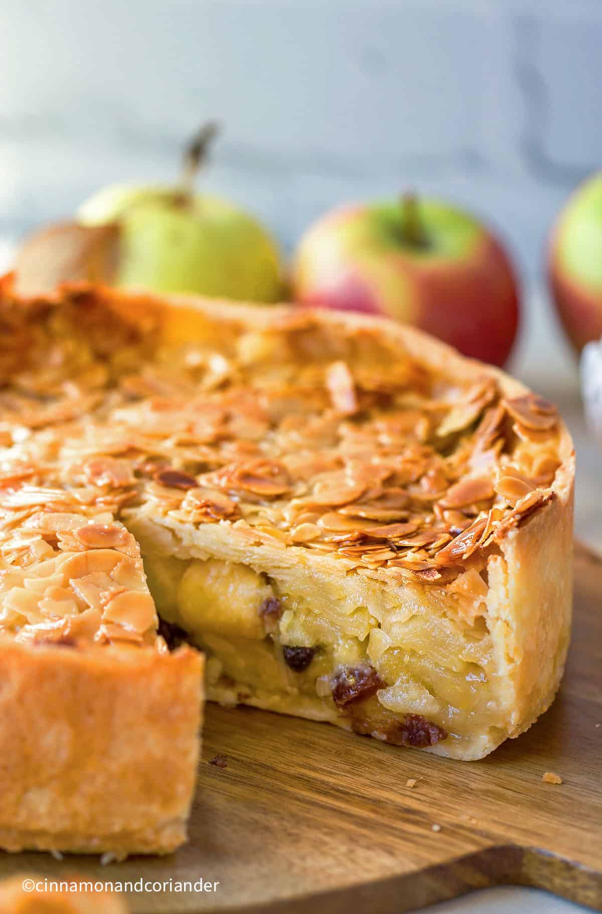 a Florentine Apple Cake with almond topping on a wooden board with one slice missing