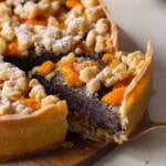 ein Stück Mohnkuchen mit Mandarinen und Streuseln auf einem Holzbrett
