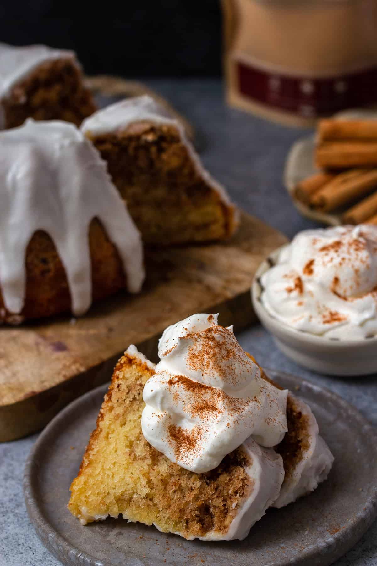 zwei stücke Zimtschnecken Kuchen auf einem kleinen Kuchenteller mit Sahne im Hintergrund