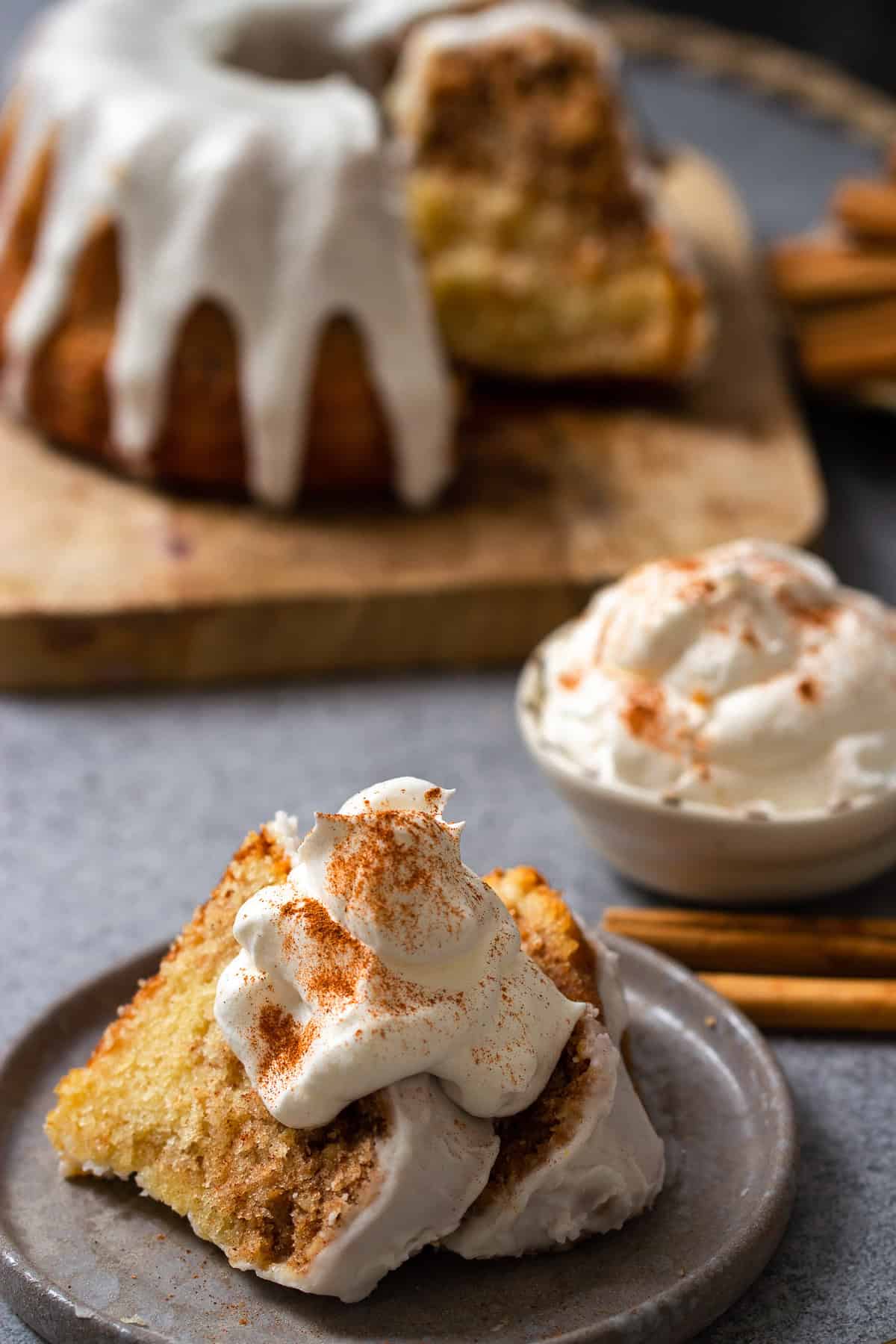 two slices of cinnamon roll bundt cake served with whipped cream on a dessert plate