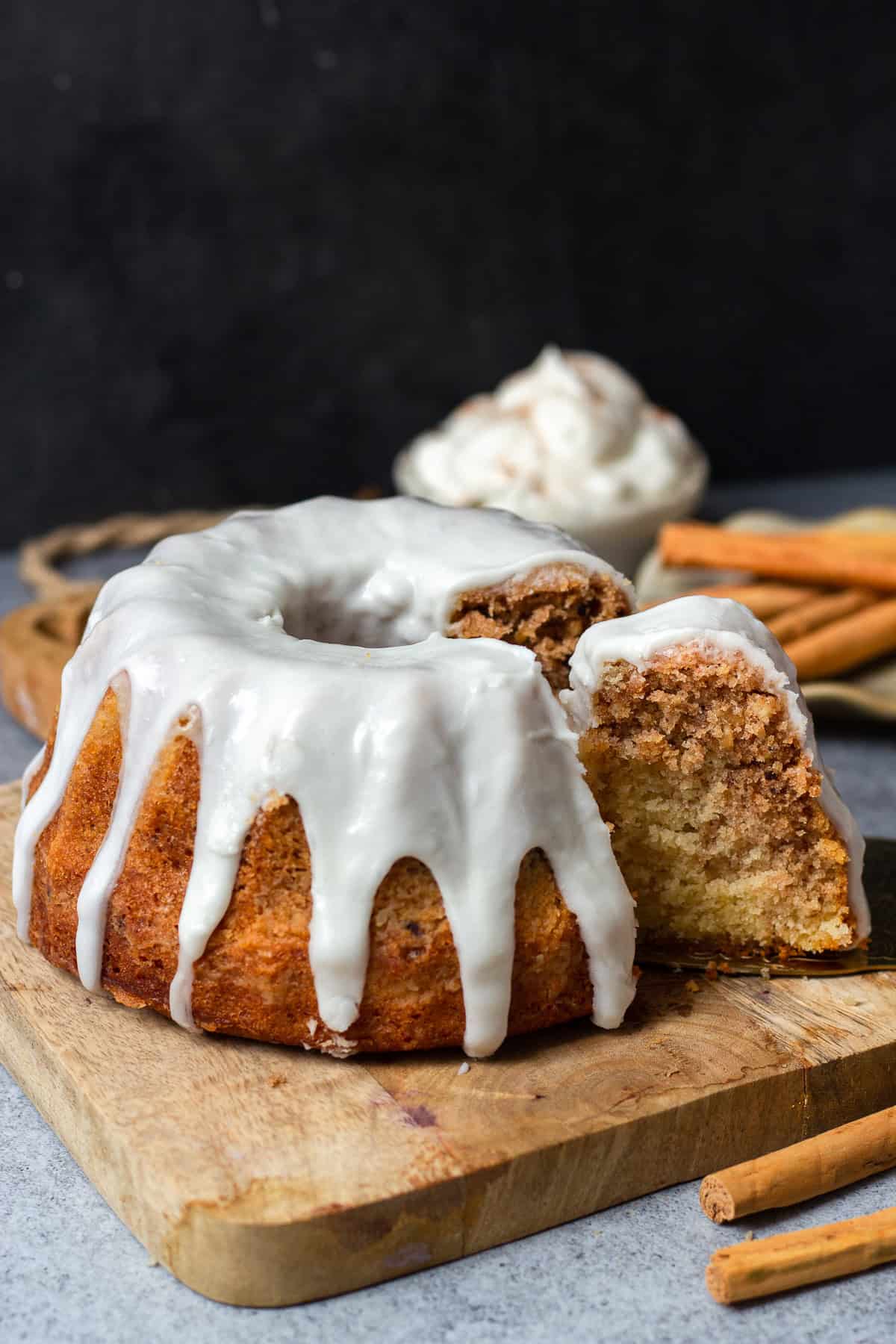 Ein angeschnittener Zimtschnecken Kuchen mit Zimt-Swirl, gerösteten Haselnüssen und Zuckerguss auf einem Holzbrett