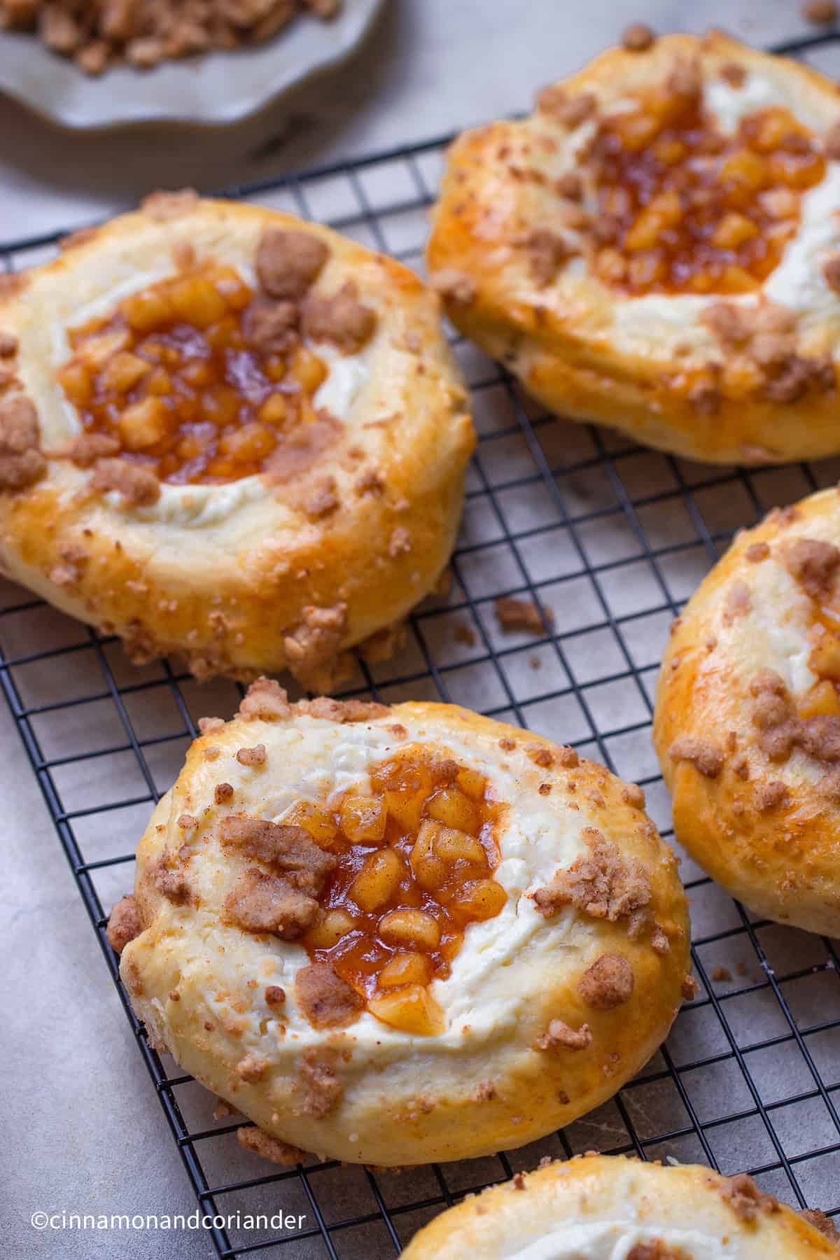 close up of Apple Cheesecake Buns with Cinnamon Crumble Topping on a black cooling rack 