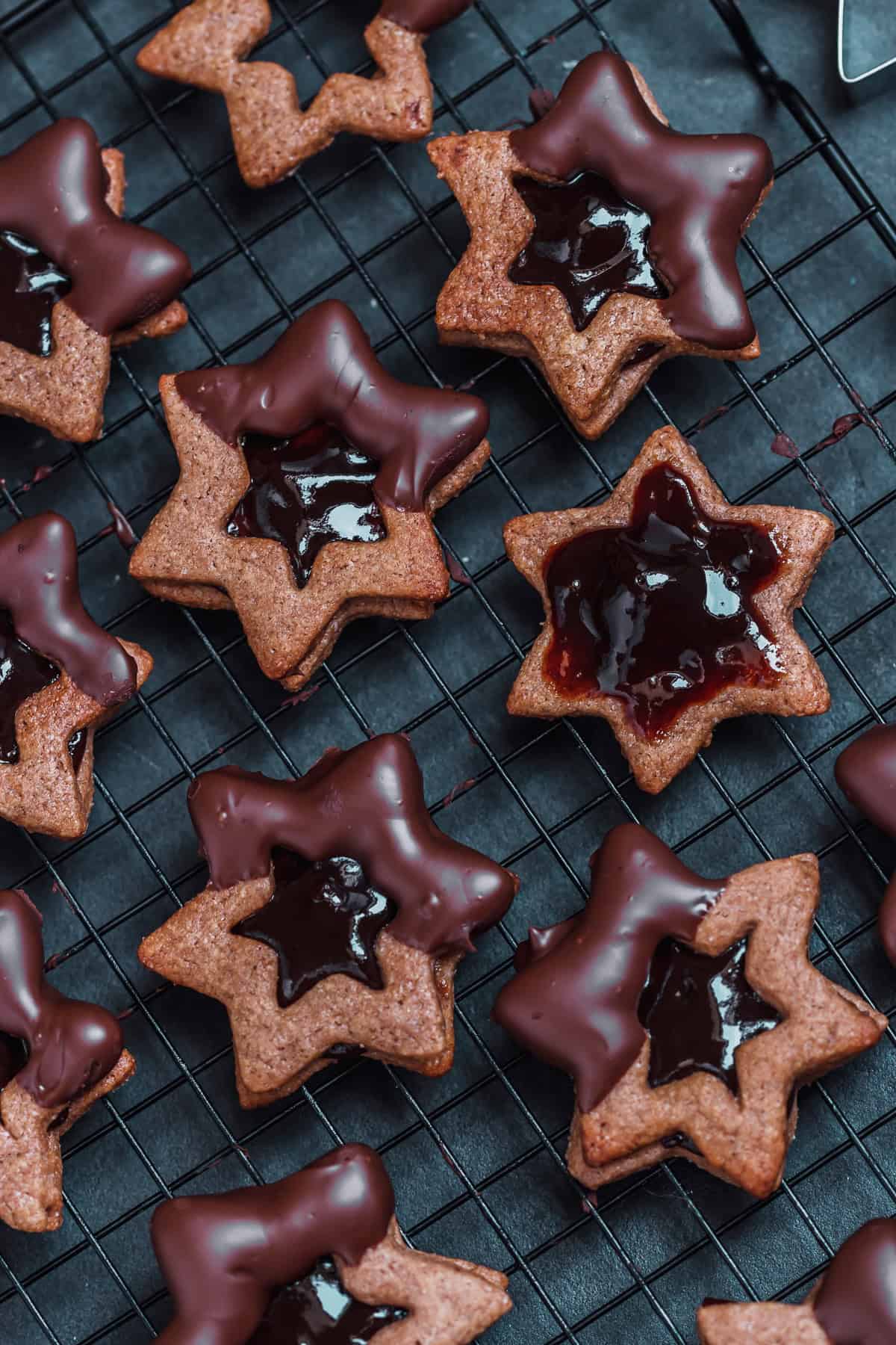 gefüllte Zimtsterne Plätzchen mit Pflaumenmus Marmemelade mit Schokoladen Glasur auf einem Gitter 