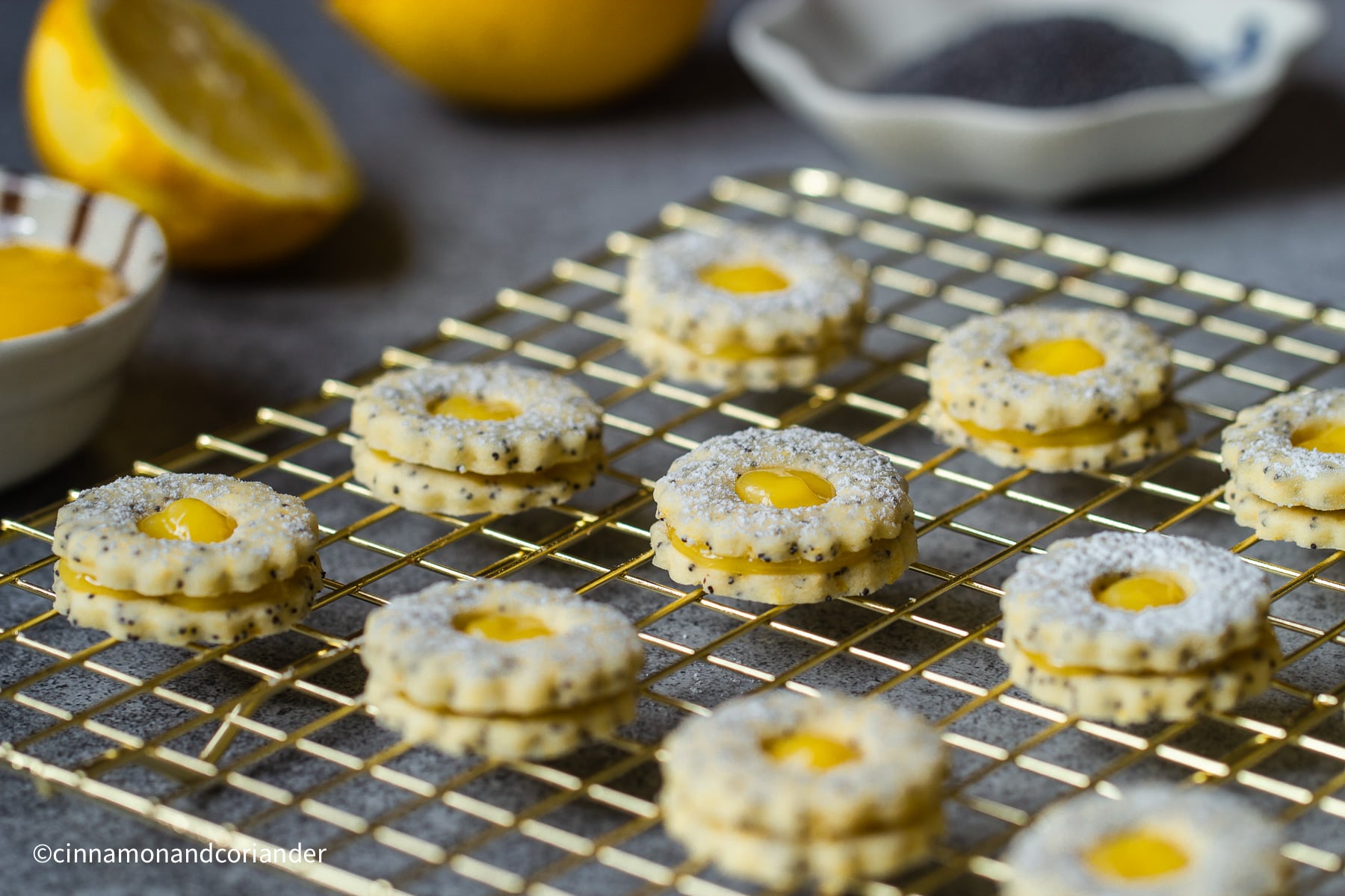 Seitenansicht von kleinen Mohn Plätzchen mit Lemon Curd gefülltauf einem goldenen Gitter