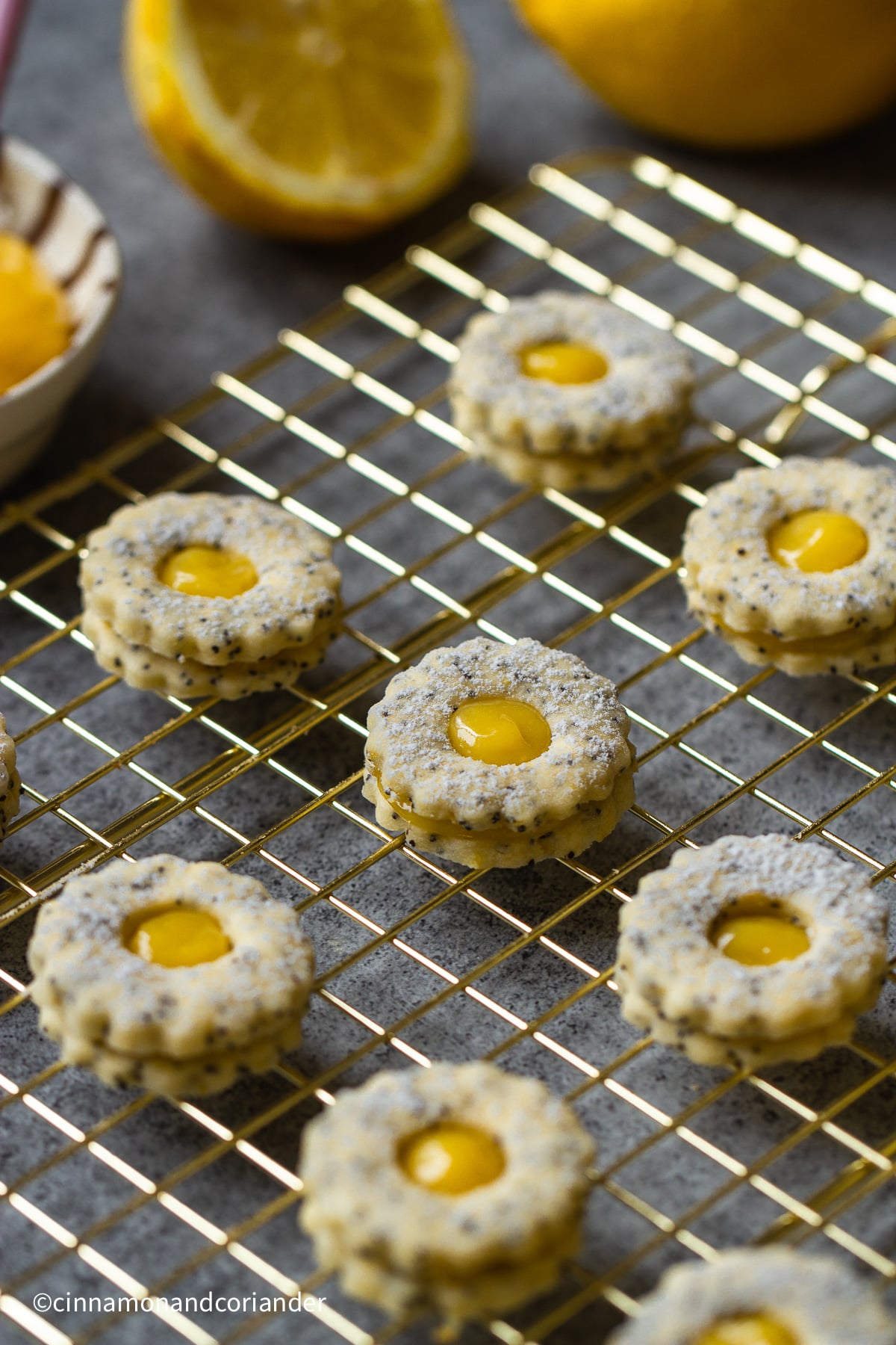 kleine runde Mohn Plätzchen mit Lemon Curd gefülltauf einem goldenen Gitter